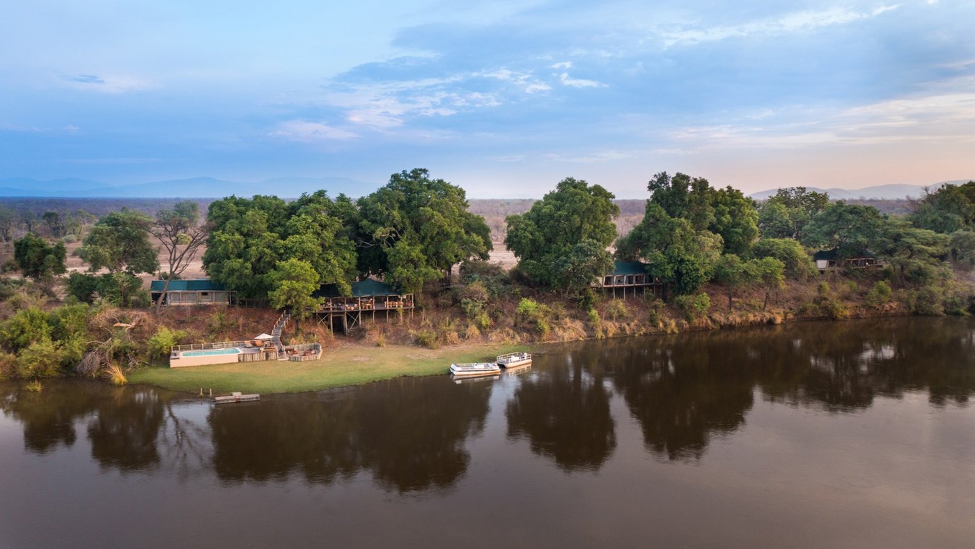Les suites riveraines d'Amanzi et la piscine nichées parmi les arbres au crépuscule du Lower Zambezi.