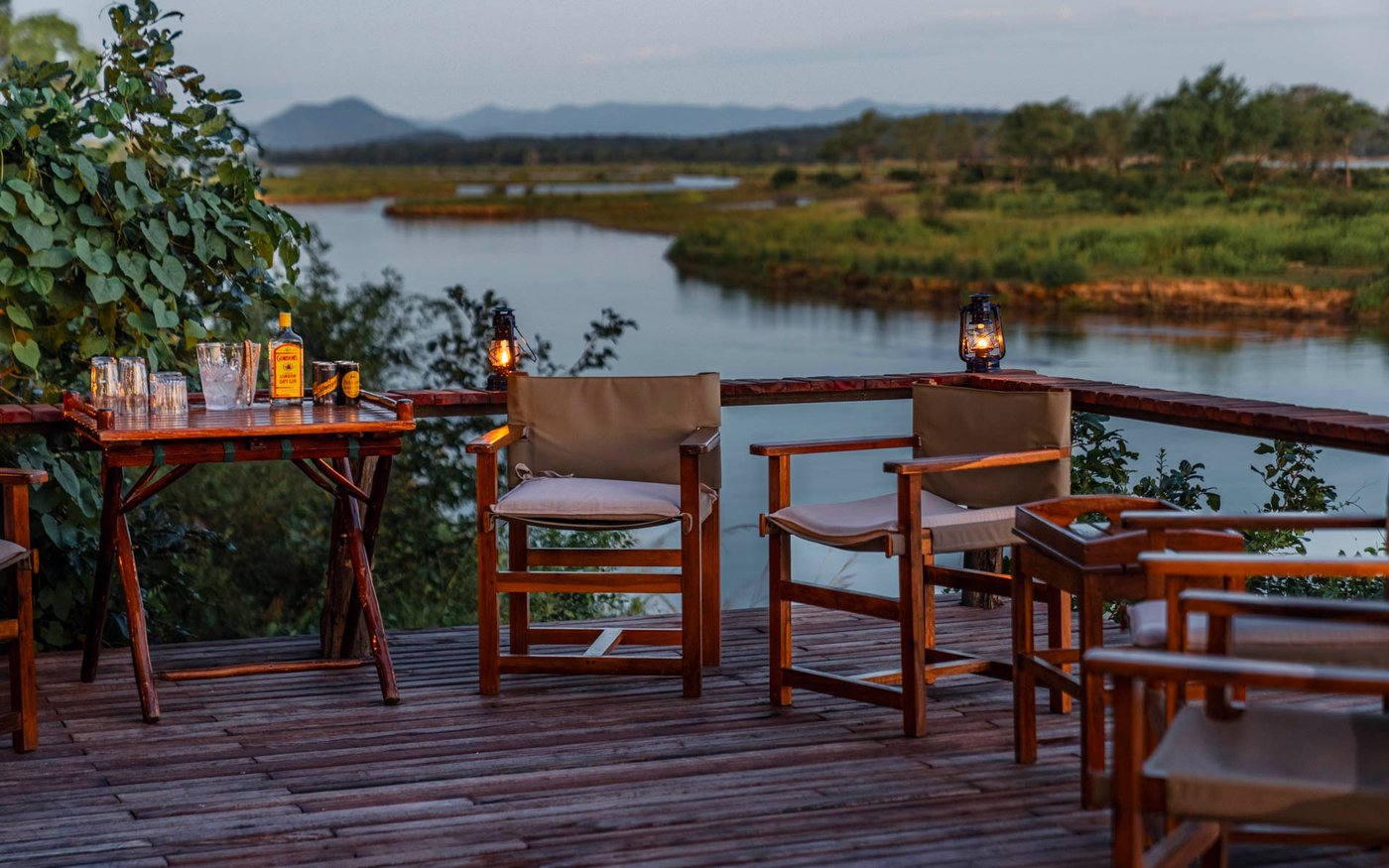Safari-Stühle und Laternen auf der Terrasse mit Blick auf die Überflutungsebene im Abendlicht von Amanzi.
