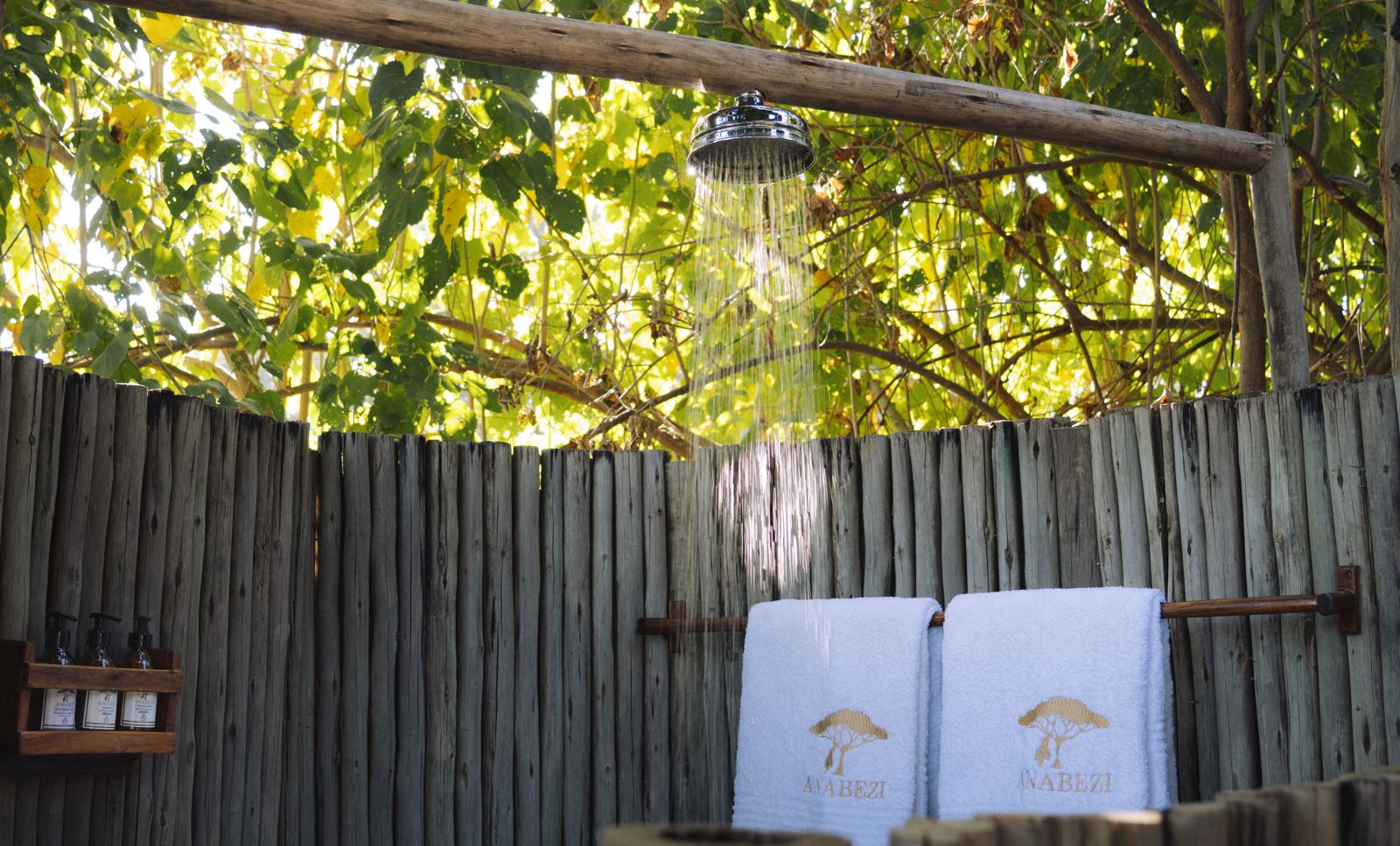 La douche extérieure, écranée par un mur en bois sous les arbres