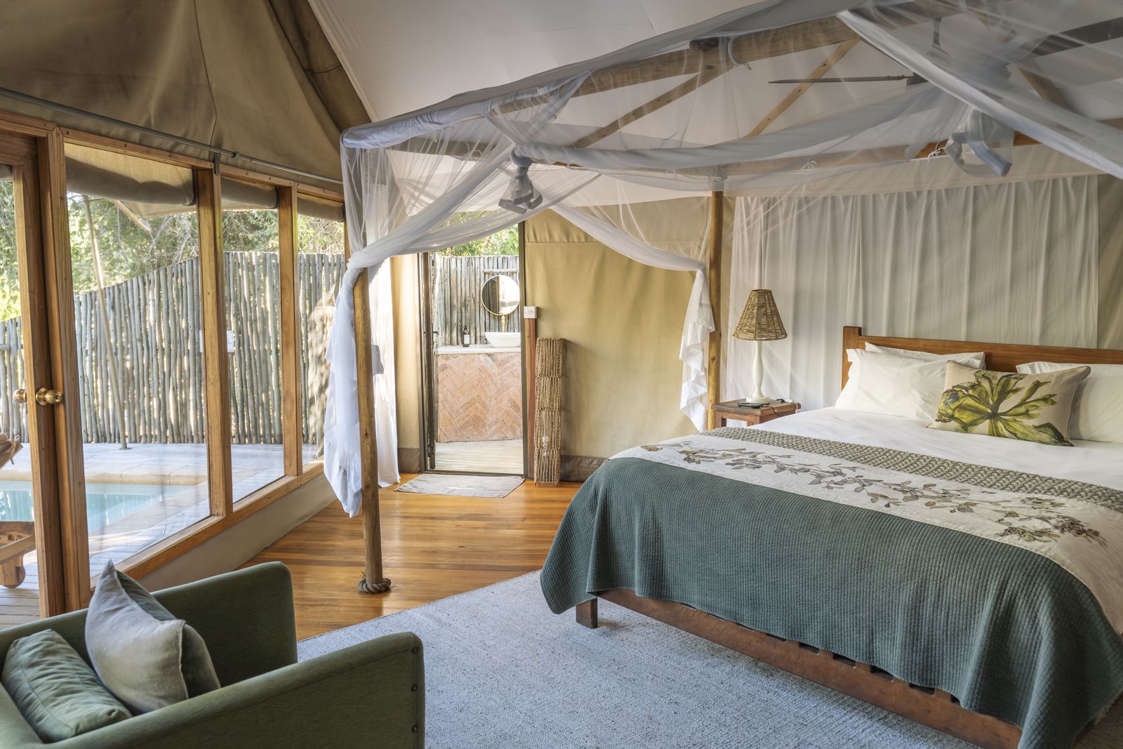 À l'intérieur d'une suite : le lit sous une moustiquaire, avec des portes vitrées donnant sur la terrasse