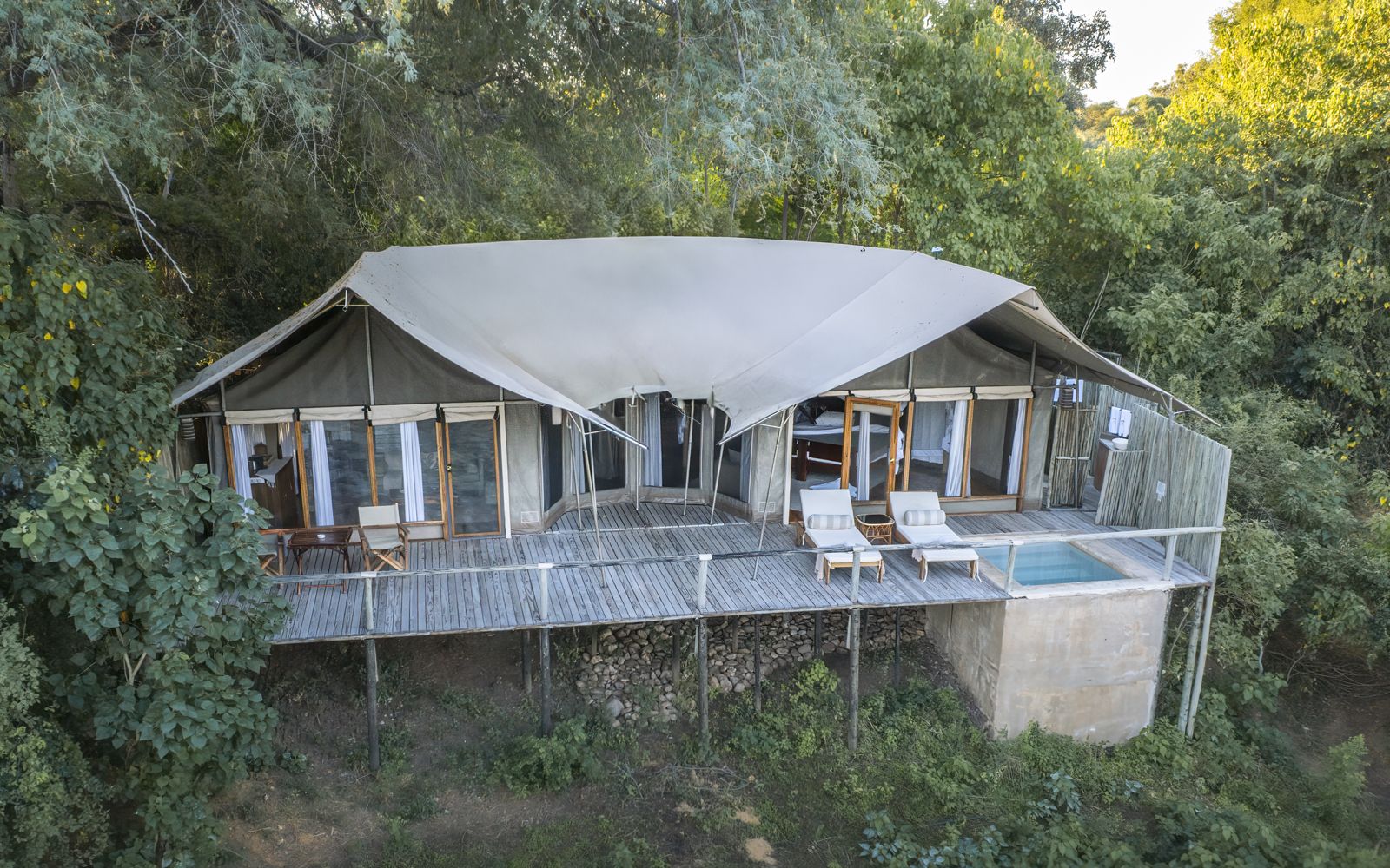 Une suite vue de l'extérieur : murs en toile, une terrasse large et une piscine plongeante privée
