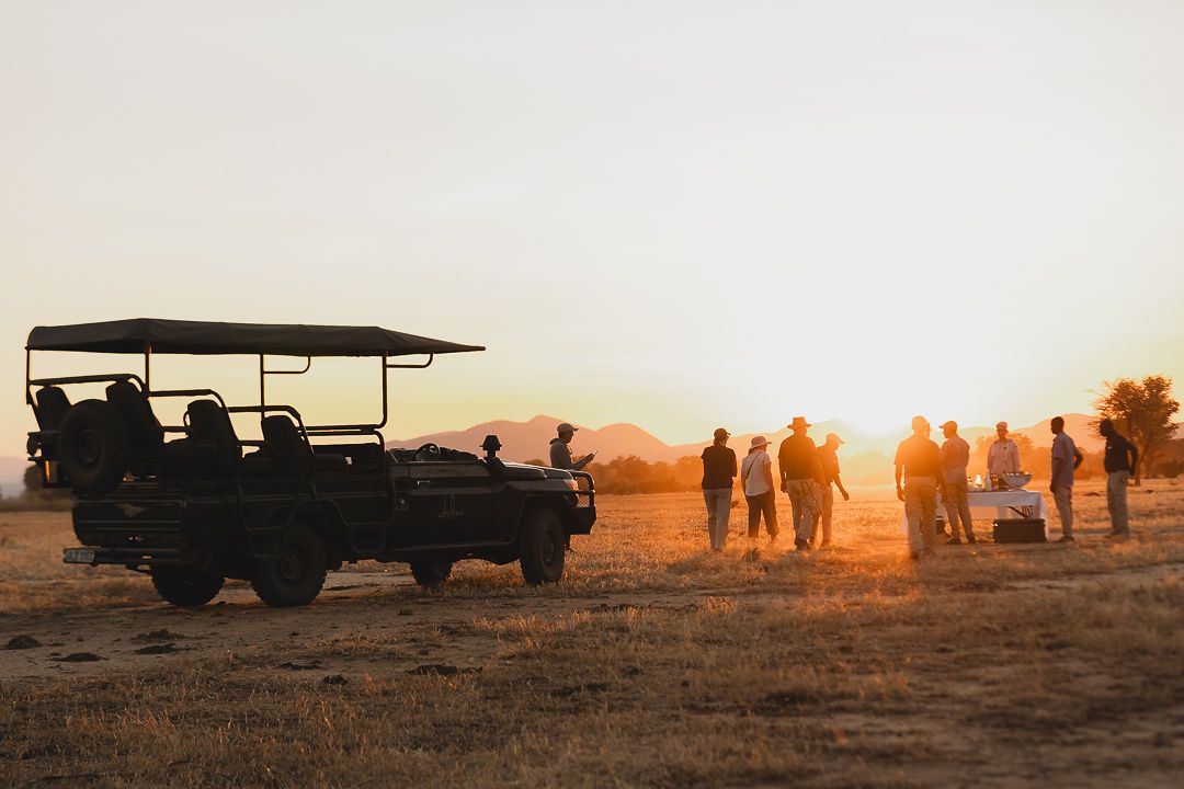 Des clients à un arrêt pour le sundowner à côté du véhicule de safari en 4x4