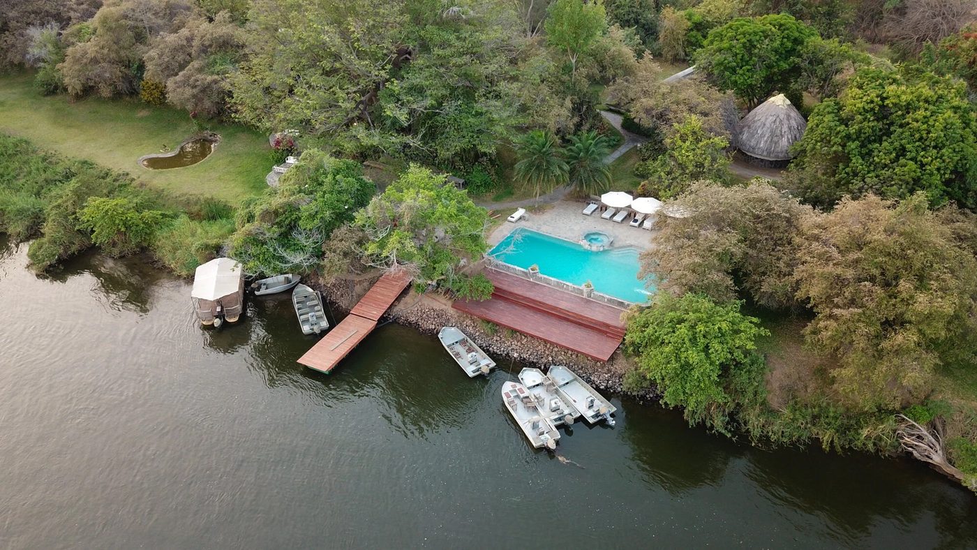 Une vue aérienne de la piscine de Kanyemba Lodge et des bateaux sur la rive du fleuve dans le Lower Zambezi.