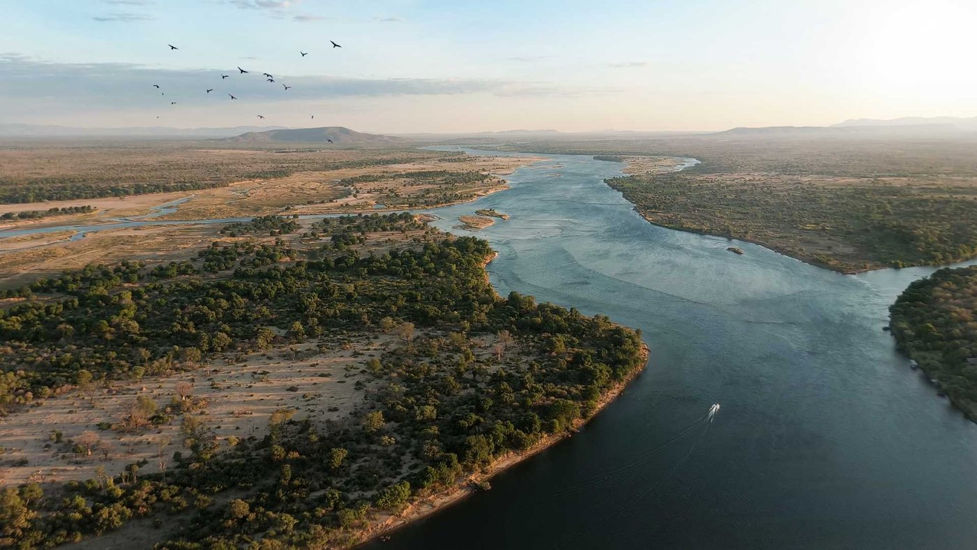 Eine Luftaufnahme des Zambezi, der sich bei Sonnenuntergang an Schilfbetten vorbeibeugt, in der Nähe von Kiambi Safari Lodge.