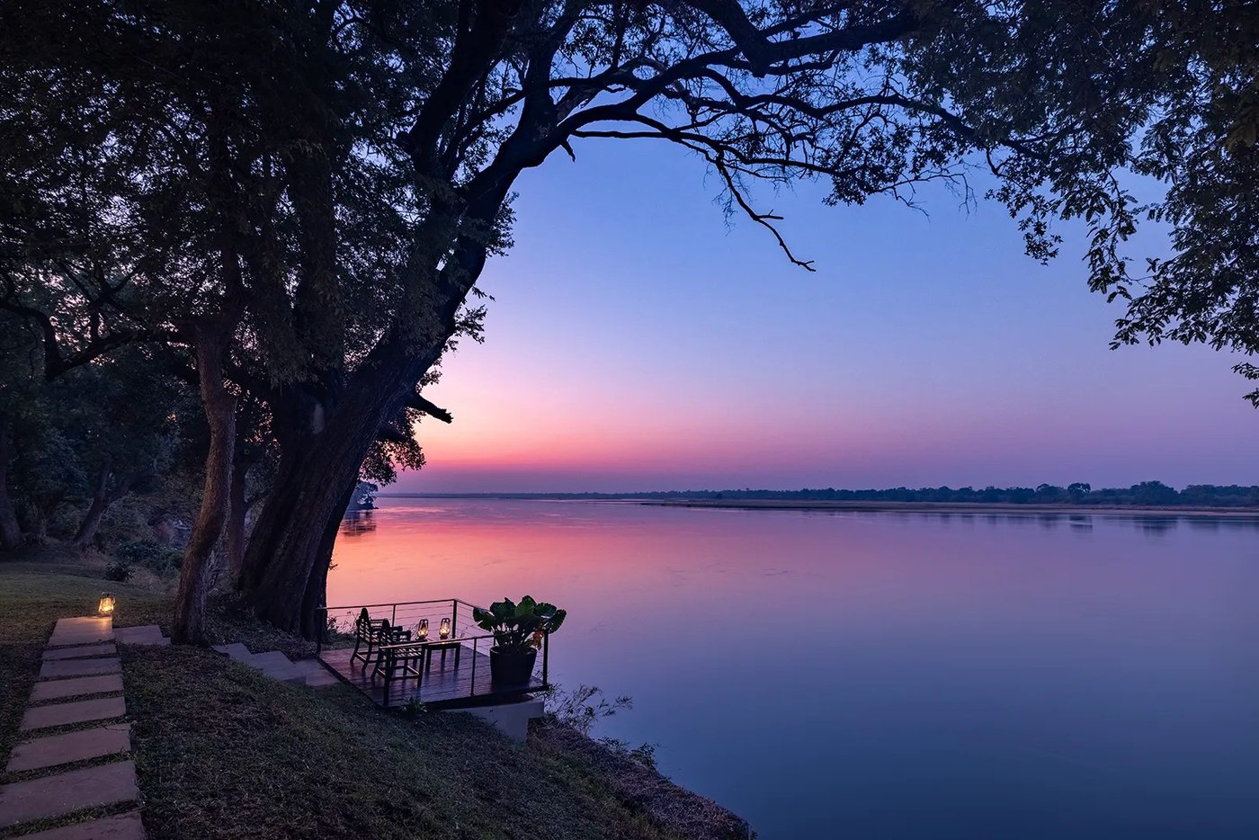 La terrasse en bord de rivière du Muchichili Safari House donne sur le Zambèze au crépuscule en Lower Zambezi.