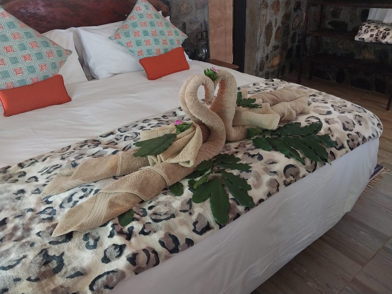 Handtuch-Schwäne liegen auf Leoparden-Bettwäsche in einem Chalet in Mvuu Lodge