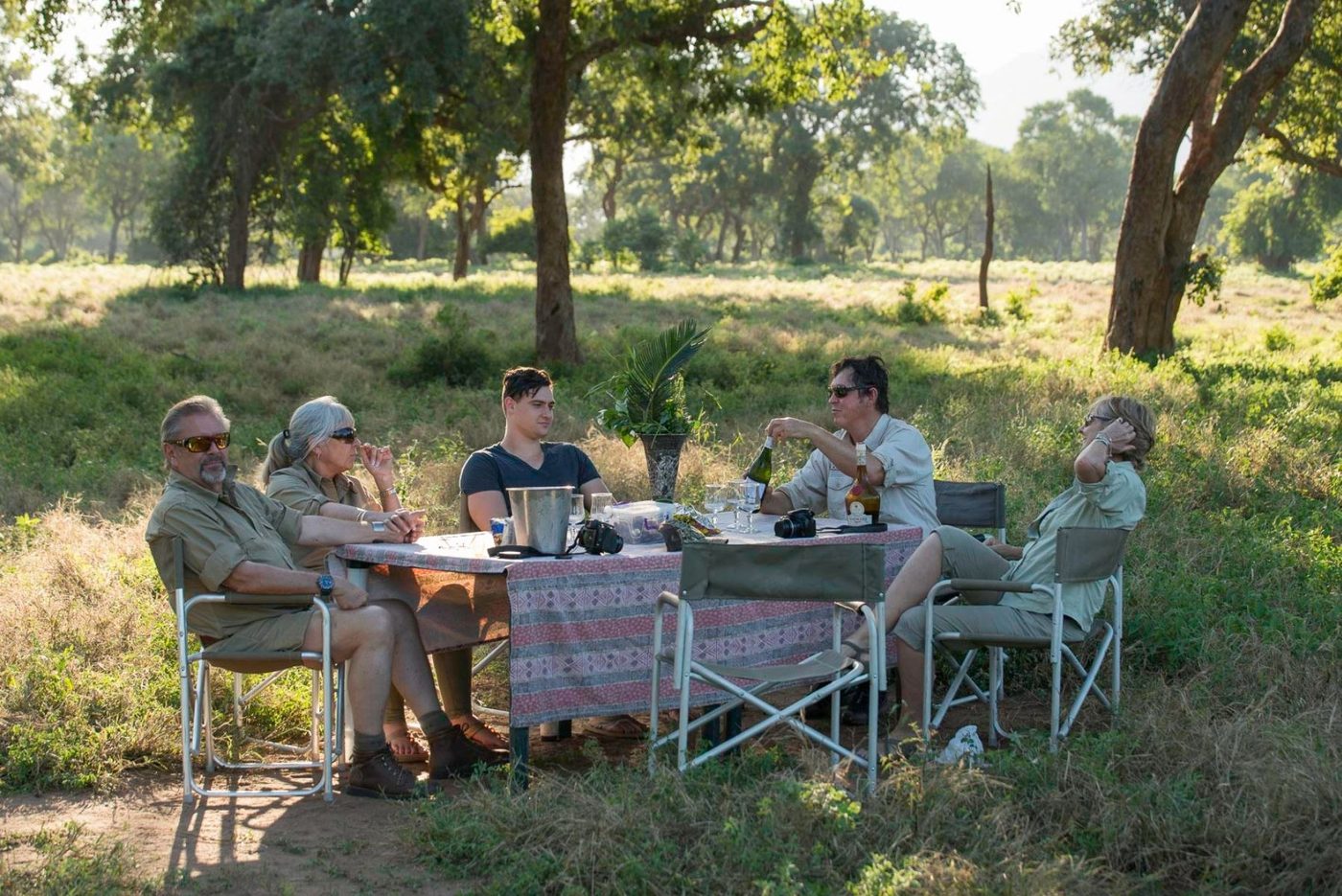 Gäste genießen ein Bush-Lunch an einem schattigen Tisch neben Mvuu Lodge