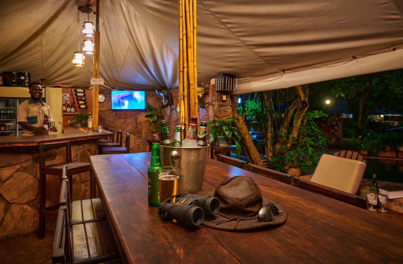 Des jumelles et un chapeau reposent sur la table du bar rustique à Redcliff Zambezi Lodge.