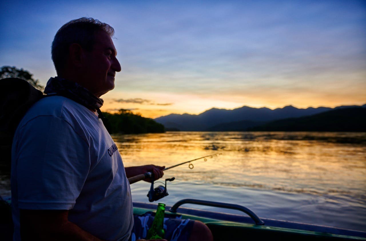 Un hôte pêche du bateau au coucher du soleil près de Redcliff Zambezi Lodge.