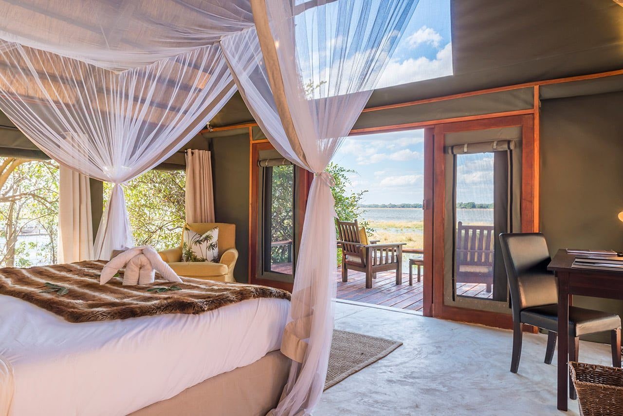 Un lit à baldaquin s'ouvre sur la terrasse et la vue sur la plaine inondable à Royal Zambezi Lodge.