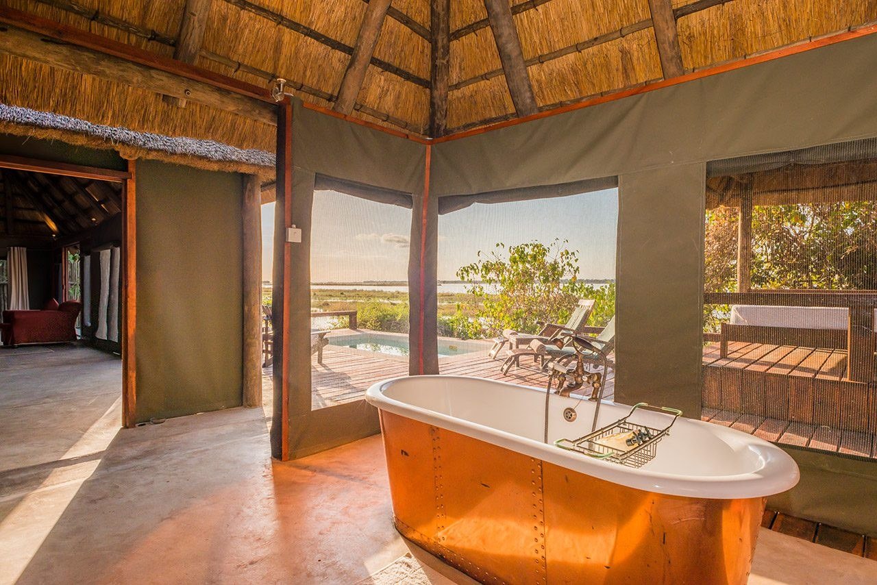 Une baignoire en cuivre se dresse dans une salle de bain ouverte avec vue à Royal Zambezi Lodge.