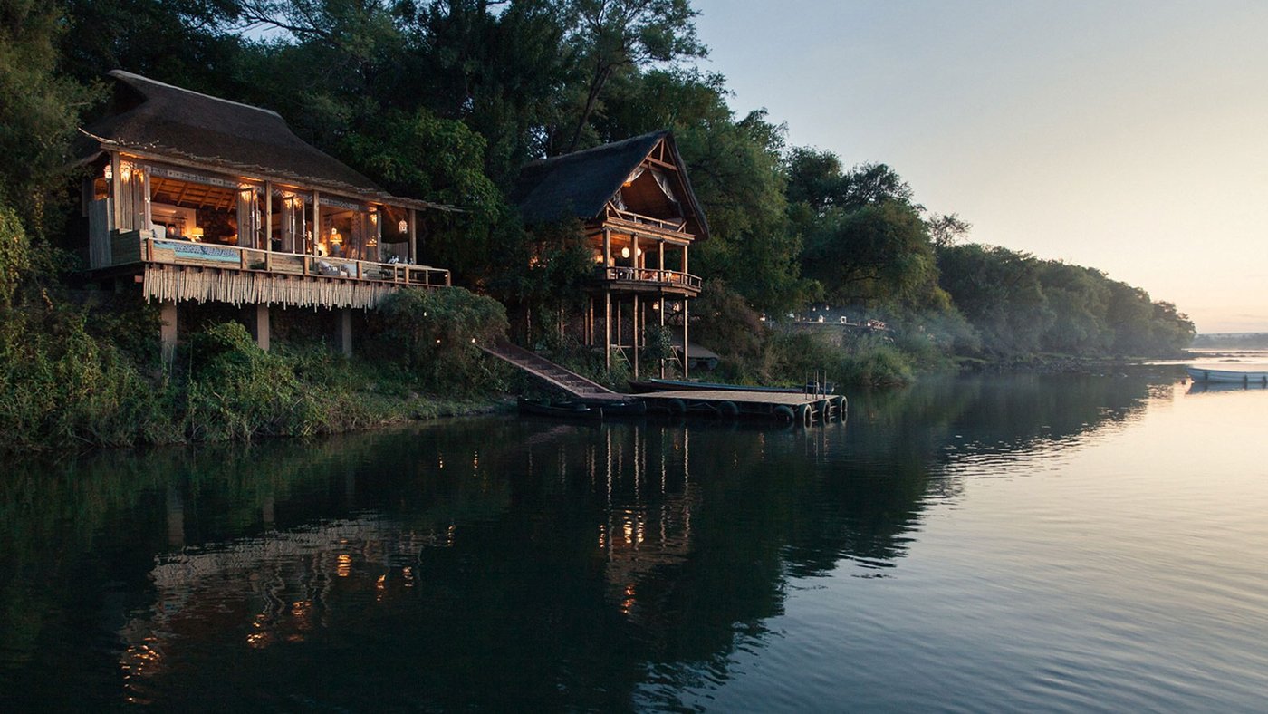 Les suites au toit de chaume du Sausage Tree Camp surélevées au-dessus du bord de la rivière au coucher du soleil dans Lower Zambezi.