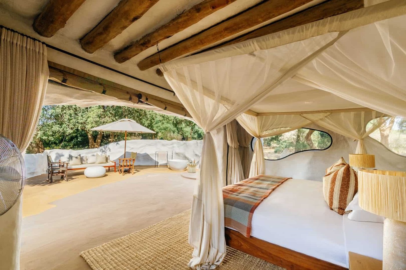 Ein Himmelbett sitzt unter runden skulpturalen Fenstern bei Time and Tide Chongwe House.
