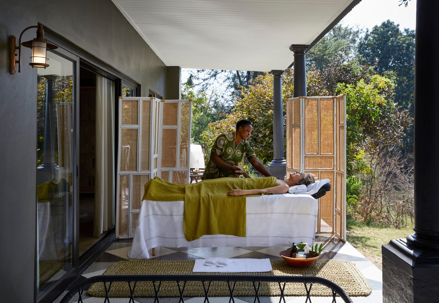 Ein Therapeut massiert einen Gast auf der Spa-Terrasse im Garten von Zambezi Grande.